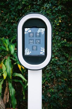 a white and black electronic device in front of some bushes