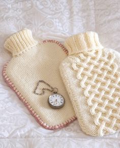 two knitted mittens are laying on a white blanket with a clock in the middle