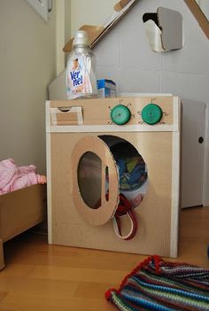 a play house made out of cardboard and some toys on the floor next to it