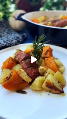 a white plate topped with potatoes and meat next to a bowl of vegetables on a table