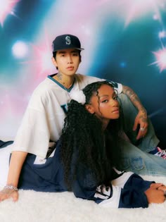 two young people sitting on the floor in front of a backdrop