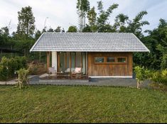 a small house with a wooden door and windows in the grass next to some trees