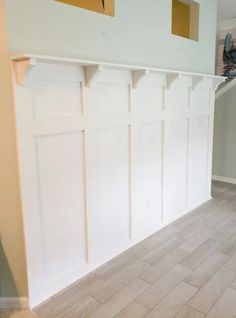 an empty room with white paneling and wood flooring in the process of remodeling