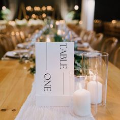 the table is set with candles and a sign that says table one next to it