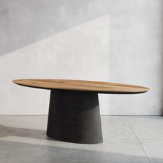 a round wooden table sitting on top of a white floor next to a wall and window