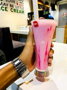 a person holding up a pink drink at a table