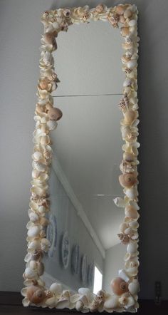 a mirror with seashells hanging on the side and an ocean themed frame around it