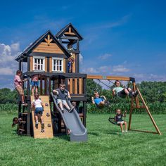 children are playing on a wooden play set in the grass with their parents and dads