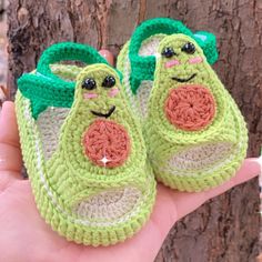 someone is holding two crocheted baby shoes in their hand while they are outside