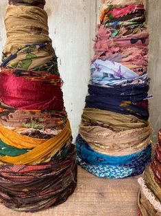 several stacks of different colored fabric sitting on top of a wooden table next to each other