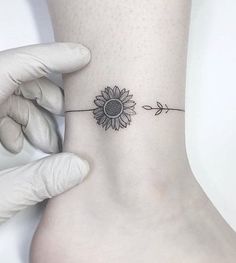 a person with a sunflower tattoo on their ankle is holding up the side of her foot