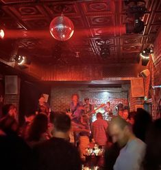 a group of people standing around in a room with red lights and disco balls hanging from the ceiling