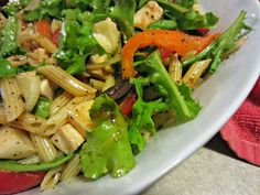 a white bowl filled with salad and dressing on top of a table next to a red napkin