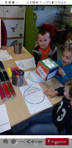 four children sitting at a table with paper and colored pencils in front of them