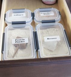 four plastic containers filled with food sitting on top of a wooden drawer next to a jar