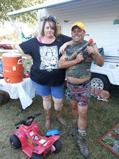 a man and woman standing next to each other in front of a tent with toys