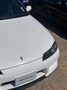 a white car parked next to other cars in a parking lot