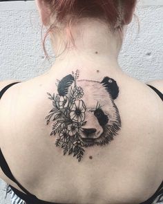 a woman's back with a panda and flowers tattoo on her upper back shoulder