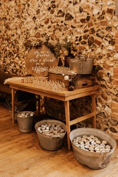 two buckets filled with food sitting on top of a wooden table next to a stone wall