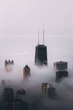 the city is surrounded by fog and skyscrapers