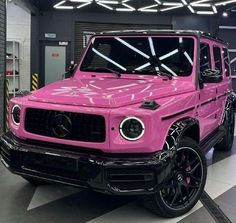 a pink mercedes g - class is parked in a garage