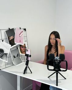 a woman sitting at a desk with a camera and tripod in front of her