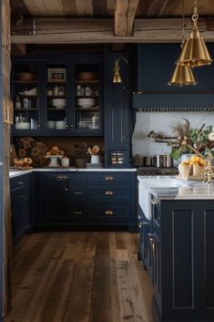 a kitchen with dark blue cabinets and wooden floors, gold pendants hanging from the ceiling