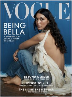 a woman sitting on top of a wooden floor next to a blue wall and magazine cover