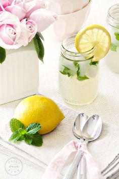 lemons, mint and water are sitting on a table with flowers in mason jars