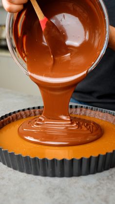 someone is dipping melted chocolate into a tart pan