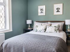 a bedroom with green walls and white bedding, two framed pictures on the wall