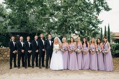 a group of people standing next to each other in front of some trees and bushes