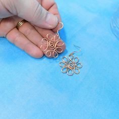 a person is holding some metal wire on a blue tablecloth with other items in the background