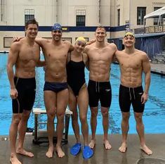 four men standing next to each other in front of a swimming pool with no shirts on