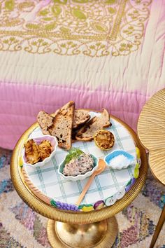 a tray with bread and dips on it sitting on a table next to a bed