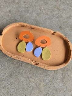 two pairs of earrings sitting on top of a brown tray with holes in the middle