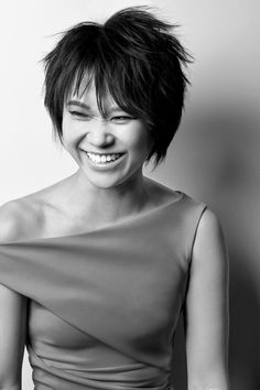 a woman with black hair smiling and wearing a red dress on top of her head