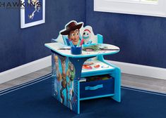 a child's table and chair with toy characters on it in a blue room