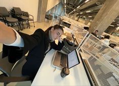 a woman sitting at a table with a laptop and cell phone in front of her