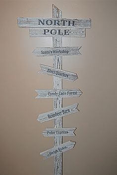 a wooden pole with several signs on it that say north pole and south pole, santa's workshop