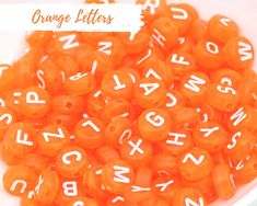 orange beads with white letters in a bowl