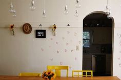 a dining room table with yellow chairs and sunflowers on the wall next to it