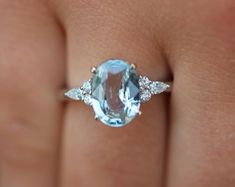 a woman's engagement ring with an aquamarine colored stone and three diamond accents