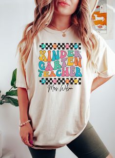 🍎✏️ Celebrate the start of the school year with our Comfort Colors® Personalized Kindergarten Teacher Shirt! This retro-inspired tee is perfect for kindergarten teachers heading back to school. Show your appreciation with a custom gift that combines style and sentiment. #KindergartenTeacherShirt #BackToSchool #ComfortColorsShirt Comfort Colors® Personalized Kindergarten Retro Teacher Shirt fits like a well-loved favorite. Super soft cotton and excellent quality print make one to fall in love with it over and over again. Custom Name Back to School Pre School Teacher Tee, Gift For Kindergarten Teacher. These are Unisex Garment-Dyed T-shirt made 100% with ring-spun cotton. Shirts look retro and vintage. The soft-washed, garment-dyed fabric brings extra coziness to your wardrobe while the rel Multicolor Letter Print T-shirt For School Events, Back To School T-shirt With Name Print For Daycare, Name Print T-shirt For Daycare And Back To School, Cotton T-shirt For Daycare And Back To School, Name Print T-shirt For Daycare With School Spirit, Back To School Teacher Appreciation T-shirt, Cotton T-shirt With Name Print For Daycare, Multicolor Letter Print Tops For School Events, Back To School T-shirt For Daycare With Crew Neck