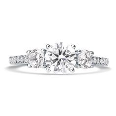 a three stone engagement ring with diamonds on the band and an oval cut diamond in the center