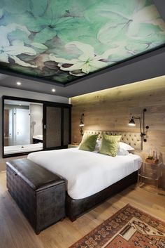 a large bed sitting under a painting on the ceiling