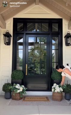 a woman bending over to pick up some flowers on the front steps of a house