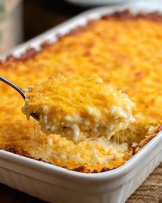 a spoonful of cheesy casserole being lifted from a white dish