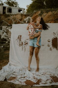 a woman holding a baby standing in front of a wall