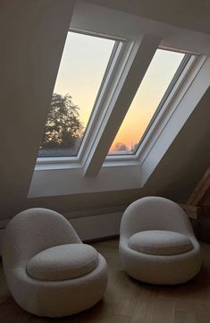 two white chairs sitting in front of a window